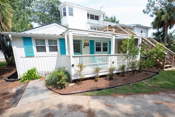 A two-story house with a porch, numbered 208, surrounded by small trees and a well-maintained lawn.