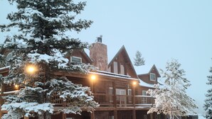 A log cabin with a wooden exterior, multiple balconies, and a snow-covered landscape. - Secluded luxury lodge that sleeps 34 in beds (Price)