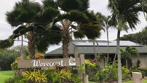 Une enseigne portant le nom « Wavecrest », entourée de plantes tropicales et de palmiers.