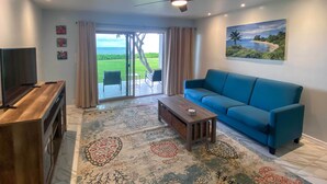 Un salon avec un canapé bleu, une table basse en bois et un meuble pour la télévision.