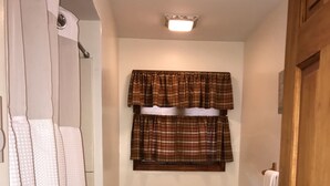 A small bathroom with a toilet, a sink, and a shower curtain. - Catskills Adventures (Roscoe)