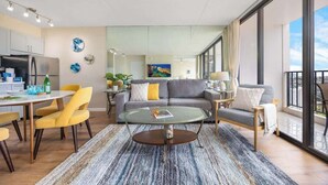 A modern living room with a glass coffee table, a sofa, and yellow chairs. - 34th floor lanai w/ pool & hot tub access (Honolulu)
