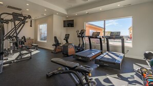 Una palestra in casa con diverse attrezzature per l'esercizio fisico, tra cui un tapis roulant, una cyclette e macchinari per pesi.