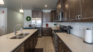 Una cucina moderna con mobili in legno scuro, elettrodomestici in acciaio inossidabile e un piano di lavoro in granito.