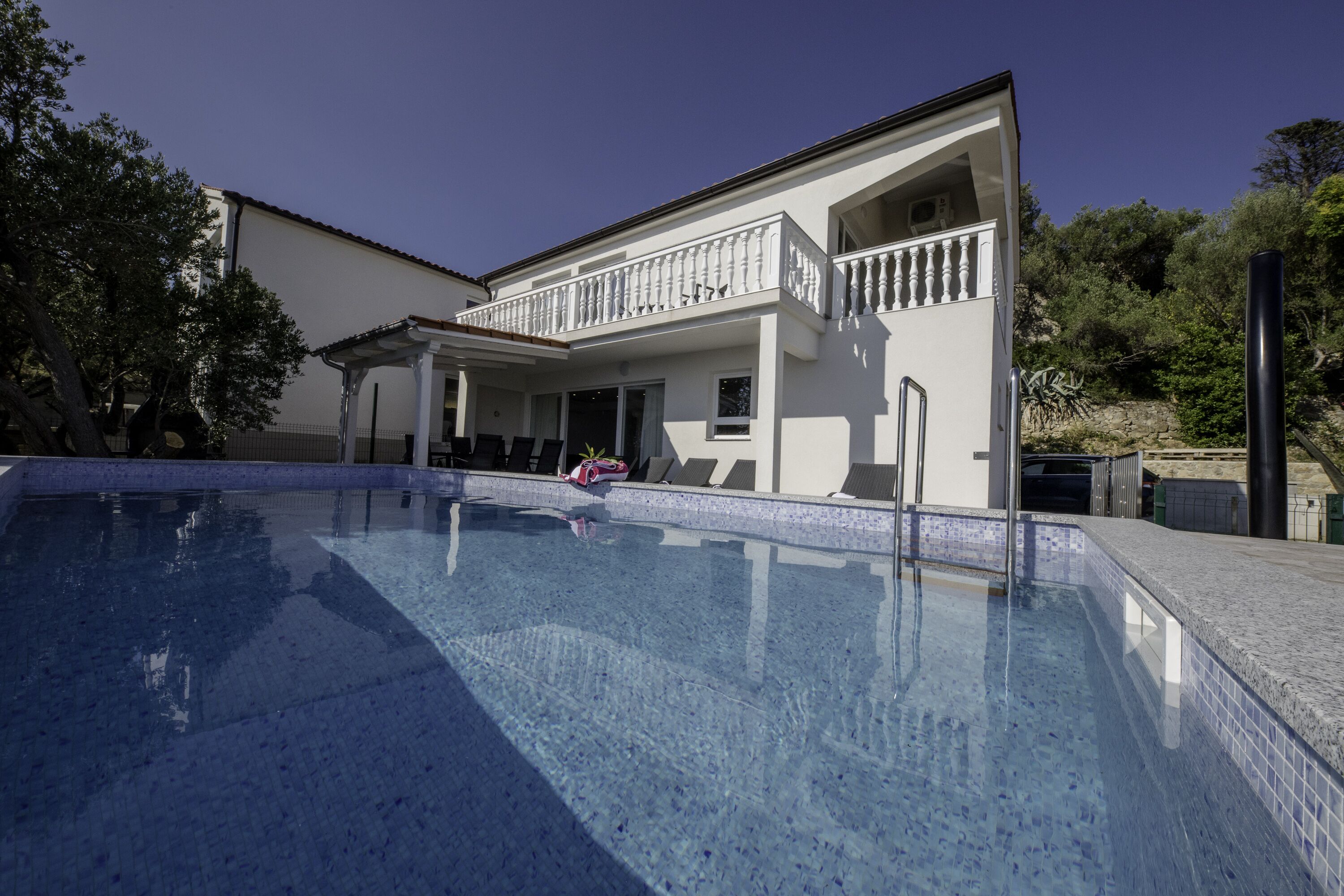 A modern house with a swimming pool, a covered patio, and a balcony.