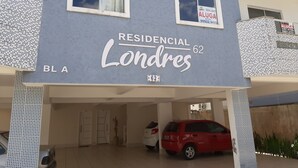A residential building named 'RESIDENCIAL Londres 62' with two windows, a parking area, and a red car parked inside.