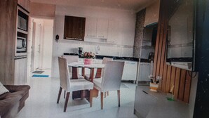 A room with a kitchenette, a dining table, and a chair.
