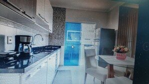 A modern kitchen with a blue door, a coffee machine, and a small table with a vase of flowers.