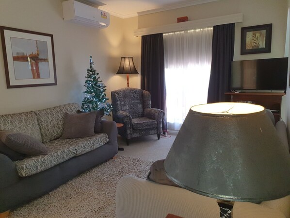 A living room with a sofa, a patterned armchair, a Christmas tree, a lamp, and a television. - BALAVIL on Fern (Fullarton)