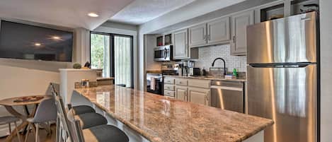 Una cocina moderna con encimeras de granito, electrodomésticos de acero inoxidable y una isla grande con taburetes de bar.