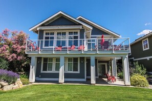 A two-story house with a balcony, a covered porch, and a well-maintained lawn.