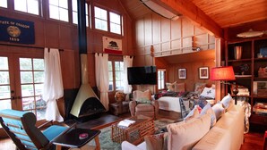 Un intérieur de chalet chaleureux avec une cheminée, un téléviseur et un coin salon confortable.
