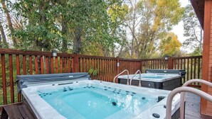 Ein Bereich mit Whirlpools, einer Holzterrasse und einem Holenzaun.