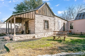 A rustic stone building with a wooden porch and a bench.