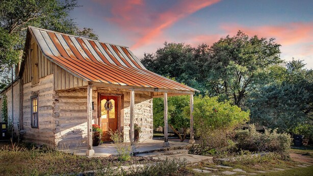 Une cabane rustique en pierre, avec un toit en métal, une véranda en bois et une plaque portant le numéro « 105 ».