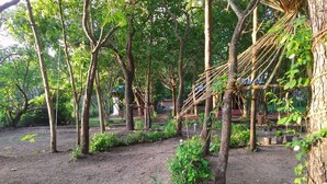 Un jardín con árboles, una hamaca y plantas en macetas.
