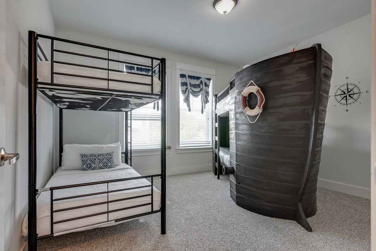 A bunk bed room with a nautical theme, including a ship-shaped headboard and a compass wall decoration.