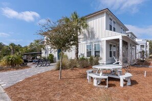 A white building with a porch and a picnic table in front.