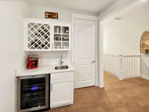 Una cocina compacta con horno integrado, un botellero y un lavamanos pequeño.