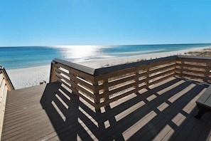 Una terraza de madera con barandilla que da a una playa.