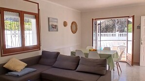 Ein Wohnzimmer mit einer Couch, einem Tisch und einem Balkonbereich mit Tisch und Stühlen.