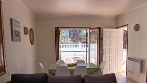 Ein Wohnzimmer mit einer Couch, einem Esstisch mit Stühlen und Blick ins Freie.