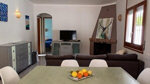 Ein Essbereich mit einem Tisch für vier Personen, einer Couch, einem Fernseher und einem Kamin.