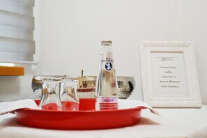 Une table avec un plateau rouge, une bouteille de Bad Liebenwerda et une carte de remerciement encadrée.