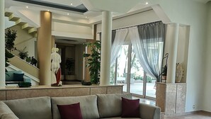 A spacious living area with a large sectional sofa, a round coffee table, and a staircase leading to an upper level. - Louis Luxury Villa (Rhodes)