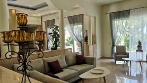 A spacious living area with a sofa, coffee table, and decorative lamps. - Louis Luxury Villa (Rhodes)