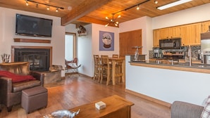 A living room with a fireplace, leather sofa, and wooden dining table. - Easy Mountain - Mt Crested Butte (Crested Butte)