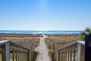 Walk along the beachfront path, flanked by railings, to the ocean's edge.
