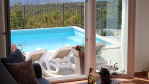 A balcony with a pool, white lounge chairs, and a view of a mountainous landscape. - Holiday Home-big Swimming Pool-amazing Views (Kraljevica)