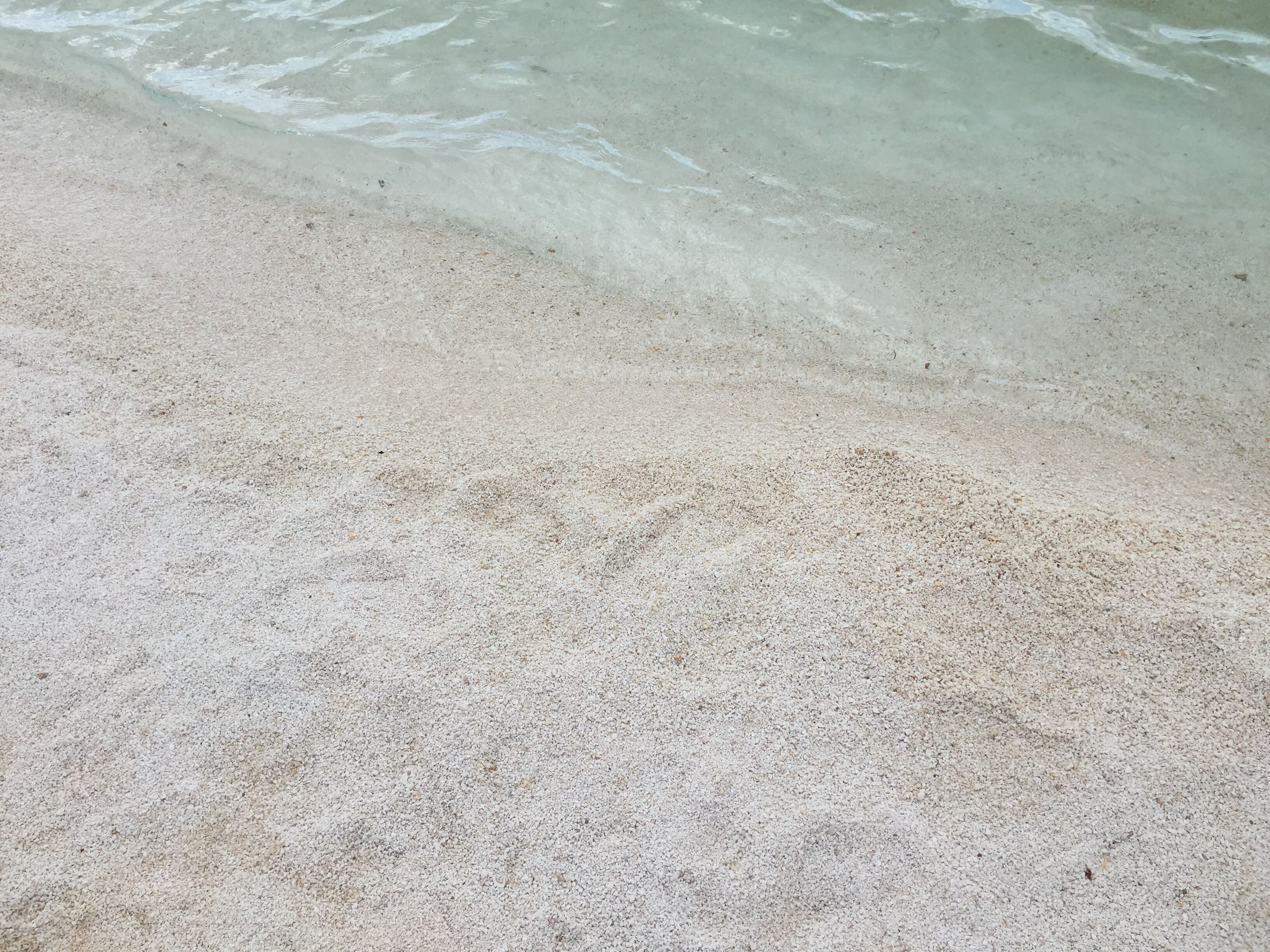 Ein Sandstrand mit klarem Wasser.
