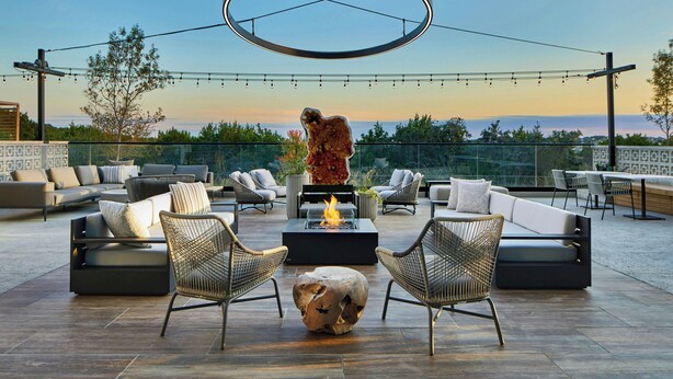 An outdoor patio with a fire pit, seating area, and string lights. - AC Hotel by Marriott Austin Hill Country (Austin)