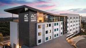 A modern hotel with a flat roof, large windows, and a prominent "AC Hotels Marriott" sign. - AC Hotel by Marriott Austin Hill Country (Austin)