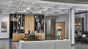 A modern interior with a central seating area, a built-in bookshelf, and a dining table. - AC Hotel by Marriott Austin Hill Country (Austin)