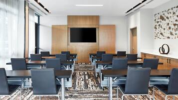 A conference room with a large TV screen, multiple tables, and chairs arranged for meetings.