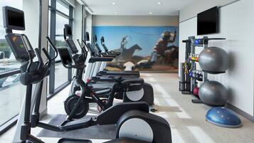 A gym with treadmills, stationary bikes, and exercise balls.
