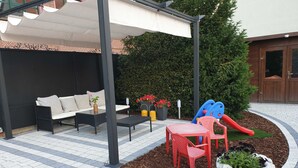 A patio area with a sofa, a table, a children's play structure, and a potted plant. - Ferienwohnung Leuchtturm 29a - Ferienwohnung (Guben)