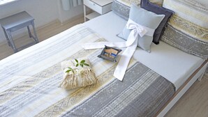 A neatly made bed with patterned bedding, pillows, and a small bedside table with a book and a clock. - Ferienwohnung Leuchtturm 29a - Ferienwohnung (Guben)