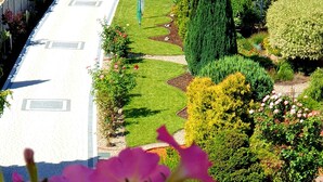 A garden with a paved walkway, neatly trimmed hedges, and a variety of flowering plants. - Ferienwohnung Leuchtturm 29a - Ferienwohnung (Guben)