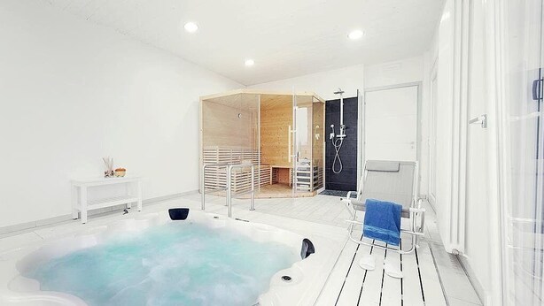 Ein moderner Wellnessraum mit Whirlpool, Holzboden und einer Duschkabine aus Glas.
