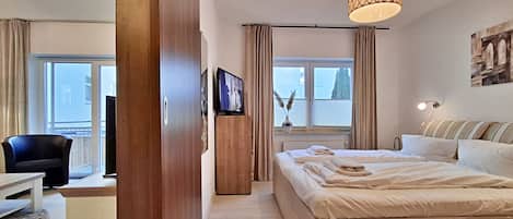 A hotel room with a bed, a desk, a chair, a television, and a window with curtains.