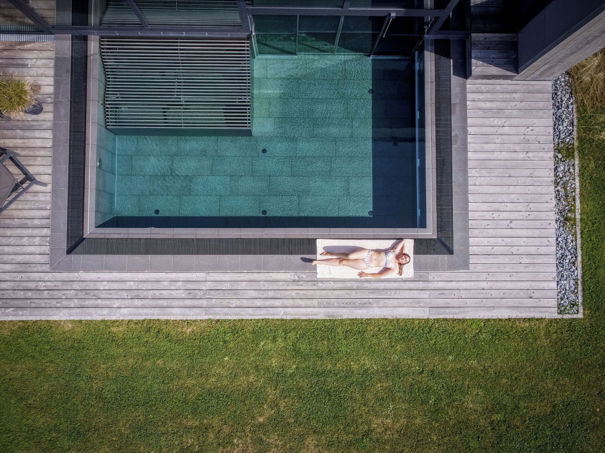 Piscina moderna ao ar livre com deck de madeira e área de estar.