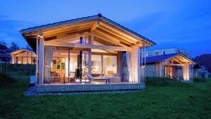Ett modernt trähus med stora fönster och en inglasad veranda.