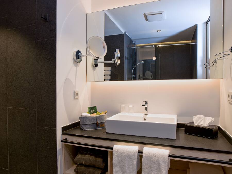 Un baño moderno con un espejo grande, un lavamanos blanco y un perchero para toallas.