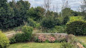 A garden with a gravel path, a stone wall, and pink flowering bushes.