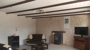 A living room with a stone wall, a fireplace, a sofa, a coffee table, and a television on a wooden stand.