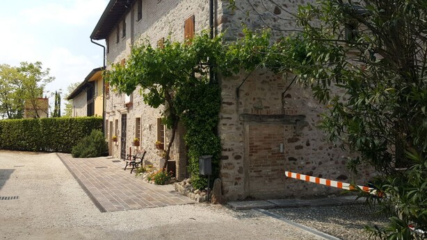 A rustic stone building with a gravel driveway and a gated entrance. - AMAZING HISTORICAL COUNTRY HOUSE (Pozzolengo)